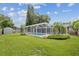 View of the home's backyard, featuring a pool and screened enclosure at 2827 Oak Tree Ln, Palm Harbor, FL 34684