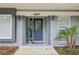 Inviting home exterior showcasing a stylish blue front door, decorative windows and an artifical palm at 2827 Oak Tree Ln, Palm Harbor, FL 34684