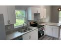 Modern kitchen with white cabinets, stainless steel appliances, and gray countertops at 11261 3Rd Ave, Punta Gorda, FL 33955