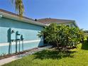 Side view of light blue house showcasing a walkway and tropical plants at 11420 Captiva Kay Dr, Riverview, FL 33569