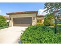 Tan house with brown garage door and lush landscaping at 243 Cassano Dr, Nokomis, FL 34275