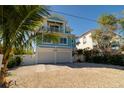 Two-story beach home with white double garage doors and light teal exterior at 2410 Avenue B, Bradenton Beach, FL 34217