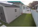 Backyard featuring a storage shed, artificial grass, and white rock landscaping at 4802 Brae Burn Ave, Sarasota, FL 34234
