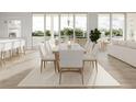 Bright dining area with a long table, seating for eight, light wood floors, and waterfront views at 3621 San Remo Ter, Sarasota, FL 34239