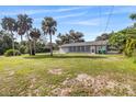 Spacious backyard featuring tropical trees and a screened in porch at rear of house at 301 Lambert St, Port Charlotte, FL 33948