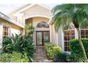 Tan house with white roof, double wood doors, and lush landscaping at 326 Saint George Ct # 14, Venice, FL 34293