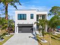 Modern two-story home with white exterior, black framed windows, and a well-maintained lawn with palm trees at 2111 Hawthorne St, Sarasota, FL 34239