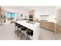 Modern kitchen with light wood cabinets, marble island, and stainless steel appliances at 4950 Remington Dr # 106, Sarasota, FL 34234