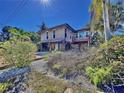 Charming raised beach cottage with lush landscaping and a teal door at 107 Los Cedros Dr, Anna Maria, FL 34216