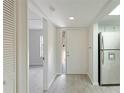 Clean entryway with wood-look floors, a white door, and built-in shelving at 4576 Ringwood Mdw # 5, Sarasota, FL 34235