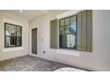 Front entry with gray door and gray shutters at 27460 Janzen Ct, Englewood, FL 34223