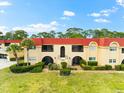 Exterior view of condo building with red tile roofs, lush landscaping, and ample parking at 209 Rubens Dr # E, Nokomis, FL 34275