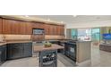 Modern kitchen with black cabinets, stainless steel appliances, wine rack, and open to the living room at 1771 Ringling Blvd # 604, Sarasota, FL 34236