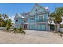 Charming two-story home with light teal exterior, paver driveway, and tropical landscaping at 118 Mangrove Ave, Anna Maria, FL 34216