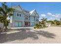Two-story teal home with paver driveway, landscaping, and gated entrance at 118 Mangrove Ave, Anna Maria, FL 34216