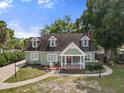 Inviting green home with classic dormers, a cozy front porch, and a neatly landscaped yard at 7754 Westmoreland Dr, Sarasota, FL 34243
