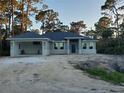 Newly constructed single-Gathering home with a two-car garage and well-lit windows, set amidst a serene, wooded landscape at 13126 Marathon Blvd, Port Charlotte, FL 33981