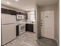 Modern kitchen with dark cabinets, white appliances, and gray tile floors at 6029 Lilli Way # 6029, Bradenton, FL 34207