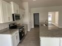 Well-equipped kitchen boasting white cabinets, granite countertops, and modern stainless steel appliances at 2679 Englewood Rd, Venice, FL 34293
