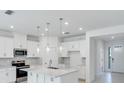 A bright kitchen with white cabinets, a quartz island, modern pendant lights, and stainless appliances at 1580 Laurel Brook Ln, Port Charlotte, FL 33953