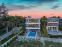 Stunning aerial view of a modern beachfront home with a pool and lush landscaping at 809 N Shore Dr, Anna Maria, FL 34216