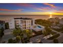 Beachfront property aerial view at sunset, highlighting modern architecture and a private pool at 89 Beach Rd # 202 & 203, Sarasota, FL 34242