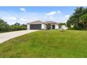 Inviting single-story home with a lush green lawn, complemented by a freshly paved driveway and a mature palm tree at 2511 Stagnaro Rd, North Port, FL 34287