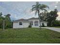 Inviting single-story home featuring a lush green lawn and mature palm trees enhancing its curb appeal at 15 Tee View Pl, Rotonda West, FL 33947