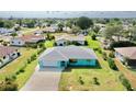 Aerial view of a charming turquoise home with a well-maintained lawn and a gray roof at 1415 Piedmont Rd, Venice, FL 34293