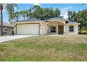 Newly built one-story house with a beige exterior and a grassy lawn at 3658 Spinner Ave, North Port, FL 34286