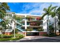 Charming condo exterior with lush landscaping, staircases, a covered garage, and beautiful plants on the balconies at 360 Gulf Of Mexico Dr # 322, Longboat Key, FL 34228