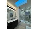 Modern bathroom with marble-look tile, skylight, and new fixtures over the vanity and in the walk-in shower at 5023 Inverness Dr, Sarasota, FL 34243
