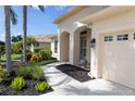 Inviting front entryway with covered porch, arched columns, and lush landscaping along the walkway at 310 Lake Tahoe Ct, Englewood, FL 34223