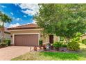 Single-story home, brown garage door, landscaping, brick driveway at 9769 Highland Park Pl, Palmetto, FL 34221