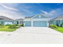 House exterior featuring a light blue three-car garage and landscaping at 14359 Skipping Stone Loop, Parrish, FL 34219