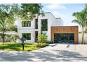 Contemporary home boasts a clean white facade, wood garage door, and lush tropical landscaping at 2226 Grove St, Sarasota, FL 34239