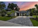 Modern single-story home with a paver driveway and landscaping at sunset at 201 S Shade Ave, Sarasota, FL 34237