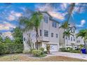 Three-story light beige home with a two-car garage and lush landscaping at 219 81St St, Holmes Beach, FL 34217