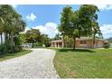 Home with a long gravel driveway, lush landscaping, and a large yard at 3225 Duncan Way, Sarasota, FL 34239
