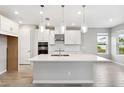 Modern kitchen with white cabinets, a large island, stainless steel appliances, and pendant lighting at 7016 Foxboro Way, Nokomis, FL 34275