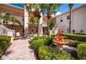 Two-story building exterior with lush landscaping, a courtyard fountain and walkway at 4244 Central Sarasota Pkwy # 725, Sarasota, FL 34238