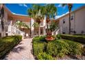 Two-story building exterior with lush landscaping, a courtyard fountain and walkway at 4244 Central Sarasota Pkwy # 725, Sarasota, FL 34238