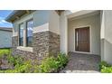 Welcoming front entrance with stylish stonework, a modern front door, and lush greenery at 429 Alberata Way, Nokomis, FL 34275
