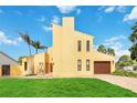Front view of a two-story yellow house with a grassy lawn and palm trees at 6515 Mauna Loa Blvd, Sarasota, FL 34241