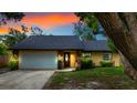 Charming single Gathering home featuring a white garage door, stone accents, and a well-maintained yard at sunset at 4175 Arrow Ln, Sarasota, FL 34232