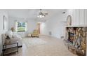 Bright living room featuring a stone fireplace, neutral furniture, tile flooring, and lots of natural light at 4175 Arrow Ln, Sarasota, FL 34232