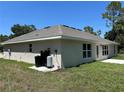 The back of a single-story home with a well-manicured lawn and an outdoor utility setup at 4012 Oscar Ter, North Port, FL 34286