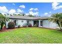 Single-story home with a lush green lawn and palm trees at 2484 Cover Ln, North Port, FL 34286