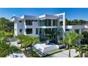 Modern white home showcasing architectural design, a glass entryway, and palm tree landscaping at 1610 N Lodge Dr, Sarasota, FL 34239