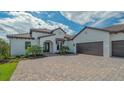 Elegant white home with tile roof, lush lawn, and paved driveway leading to a spacious two-car garage at 10629 Nicklaus Ct, Englewood, FL 34223